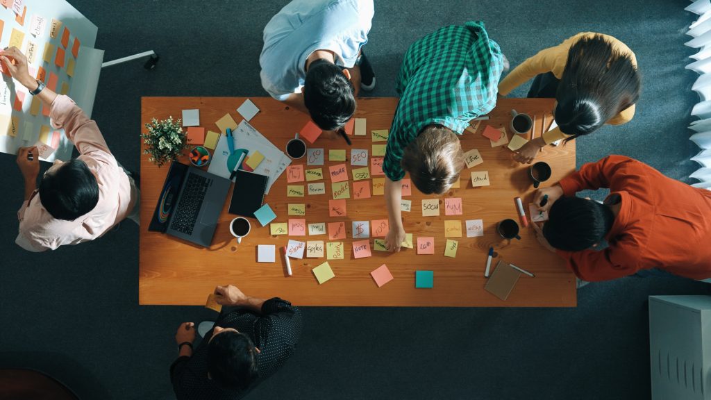 People working at a table filled with sticky notes.