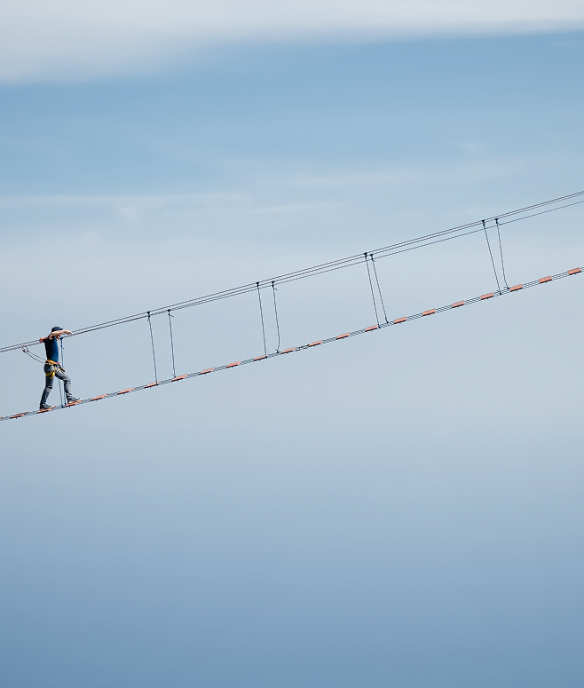 Man walking across a suspension bridge